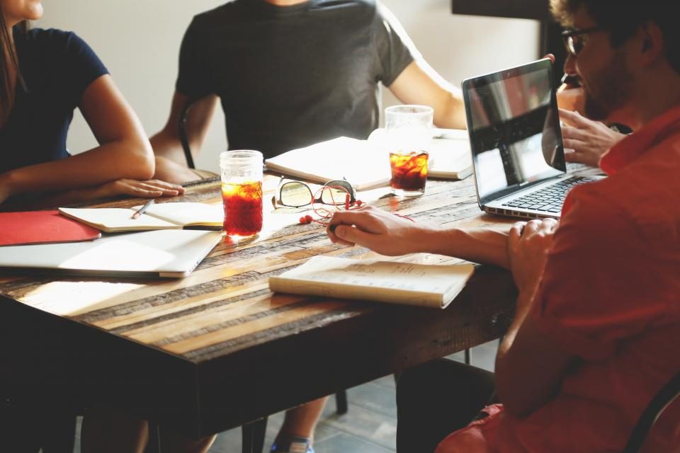 People sitting around a table with notebooks and laptops open, sharing ideas