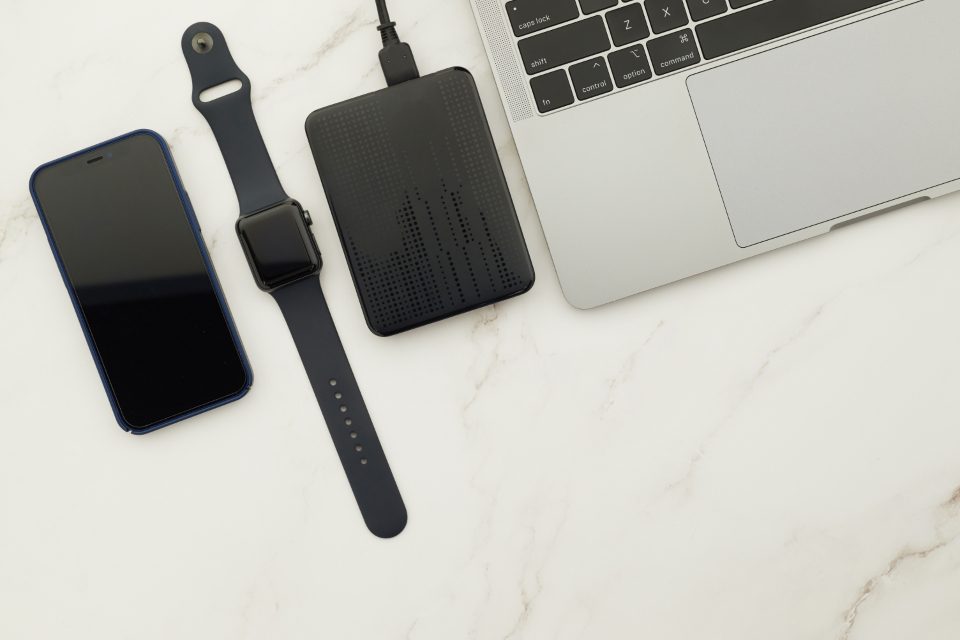 A tidy desk seen from above with a laptop, smartphone and notebook